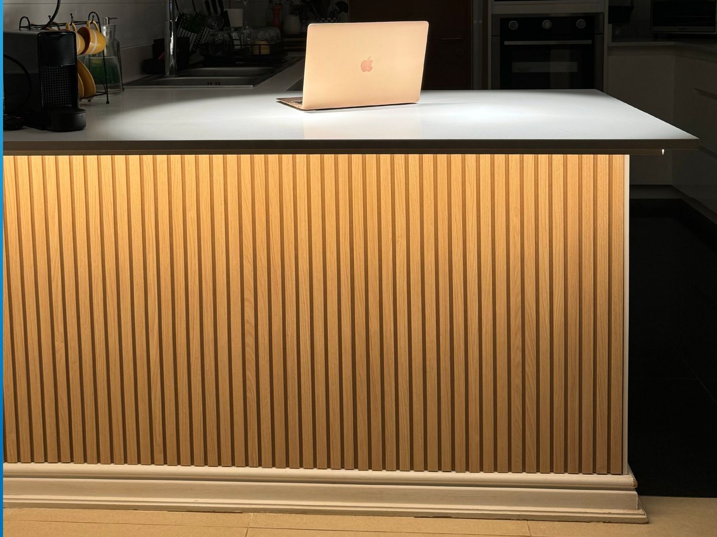 Isla de cocina revestida en listones de madera con luz LED bajo la cubierta